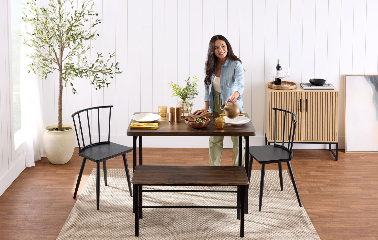Woman standing in a dining room with a wooden table and chairs.