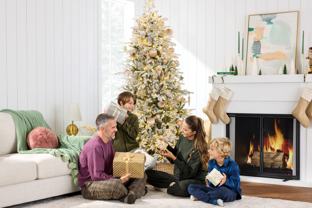 Family gathered around a Christmas tree in a living room with a fireplace.